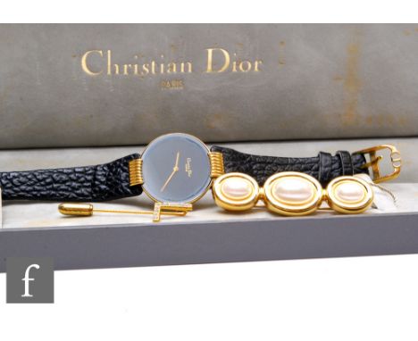 A lady's gold plated Christian Dior quartz wrist watch, gilt batons to a black circular dial, with Dior pin and brooch, all b