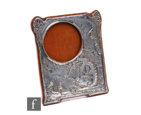 An Edwardian hallmarked silver rectangular easel photograph frame decorated with an embossed landscape scene with two figures