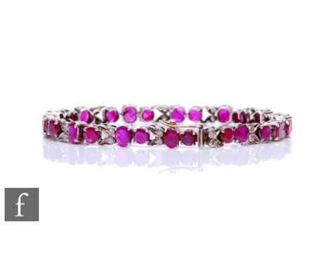 A silver ruby and diamond line bracelet with twenty seven round and oval cut rubies detailed with thirteen pairs of diamonds,