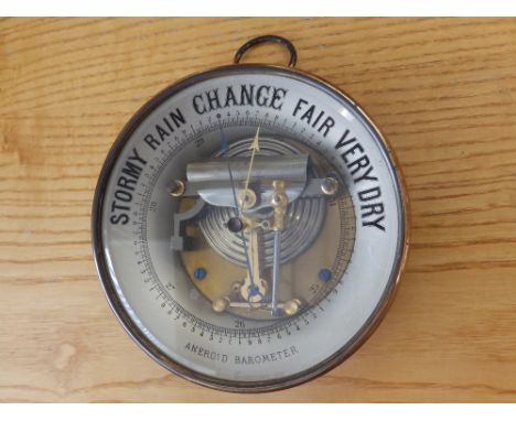 A circular brass aneroid barometer.