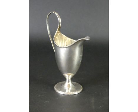 A George III silver helmet jugWith applied beaded rims, to a reeded handle, raised on a circular pedestal foot, monogrammed, 