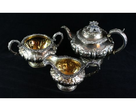 An early Victorian silver three piece tea serviceOf circular form, with an applied foliate rim, the domed lid with a cast fol