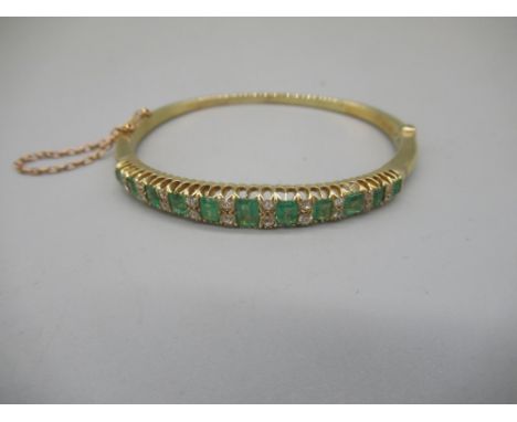 15ct yellow gold hinged bangle set with graduated emeralds cut emeralds and brilliant cut diamonds, stamped 15ct, 15.8g 
