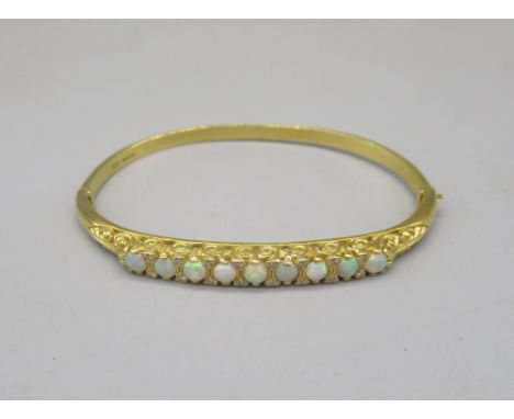 18ct yellow bangle set with nine opals between brilliant cut diamonds on scroll mount, stamped 750, with box closure, 22.4g 