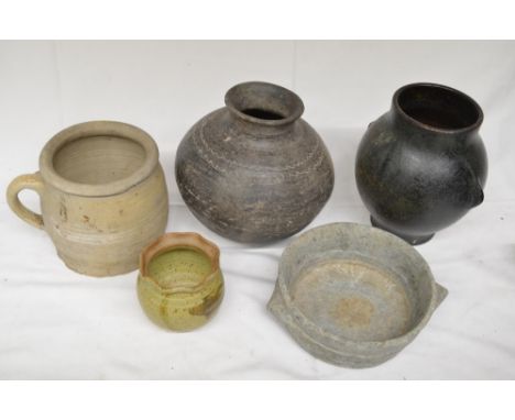 Collection of four ceramic pots, glazed and unglazed, including both antique and modern examples, and a hand-carved stone bow