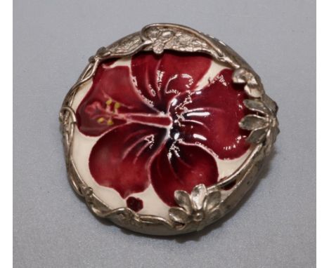 Moorcroft Pottery: ‘Hibiscus’ pattern ceramic roundel set in a silver foliate mount, mount stamped MRB, London 1989, D3.5cm 