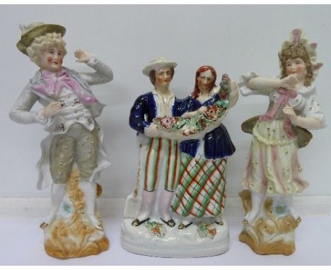 A pair of bisque figures of a man and woman and a Staffordshire figure of a couple with Bocage, height of Staffordshire figur