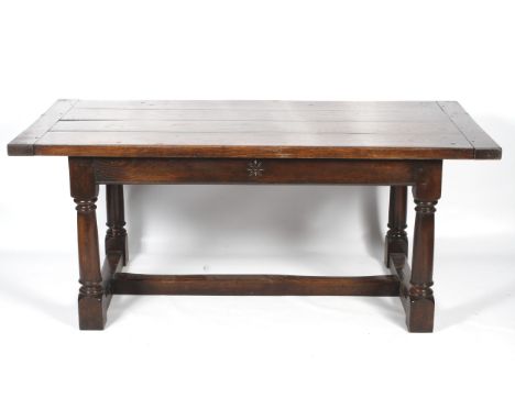 An oak plant top refectory table. The top in four planks with end stretchers, raised on turned gun barrel supports united by 