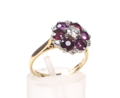 A vintage 18ct gold, ruby and diamond cluster ring. Centred with a round brilliant diamond approx. 0.18cts, within a round mi