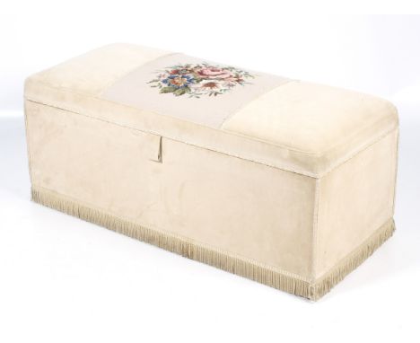 An upholstered ottoman with padded lid and later applied needlework tapestry. Upholstered in cream with tassel plinth on cast