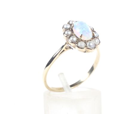 An early-mid 20th century gold, opal and half-pearl oval cluster ring. the central oval cabochon white opal displays a mostly