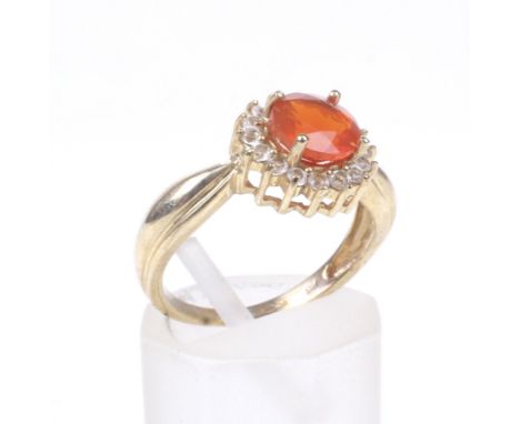 A 9ct gold, fire opal and cubic zirconia cluster ring. Centred with an orange round mixed-cut fire opal within a small round 