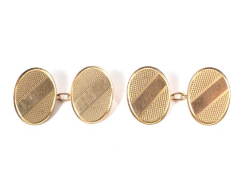 A pair of early 20th century 9ct rose gold oval twin-panel cufflinks. Each panel with a plain diagonal band between engine tu