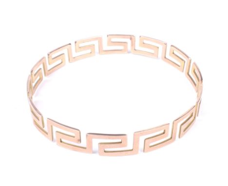 A late Victorian/Edwardian rose gold 'Greek-key' slave bangle. The open work hoop pierced with a geometric Greek key pattern,