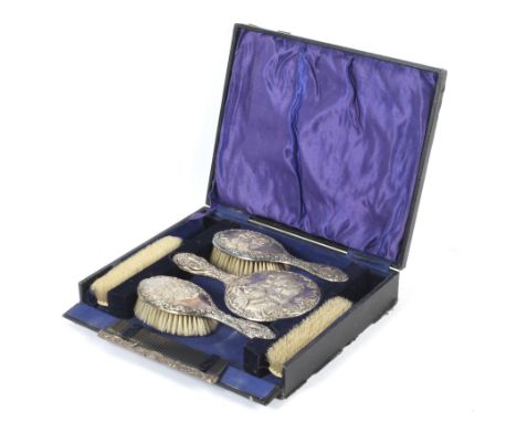 A cased six piece silver backed dressing table set. Decorated with busts of winged cherubs, comprising a hand held mirror and