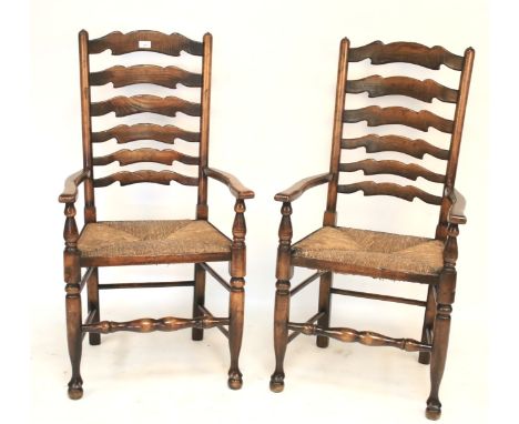 A pair of provincial rush seated ladder back armchairs. With shaped backs, scroll arms and baluster supports and stretchers, 