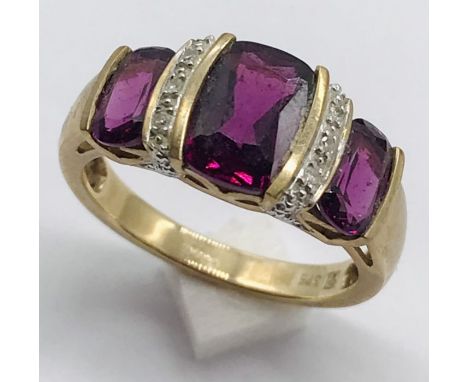 A garnet three stone ring interspersed with diamonds set in 9ct gold