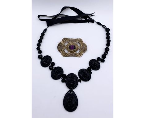 A carved Whitby jet necklace (one panel loose but present) along with a Classically style gilt brooch