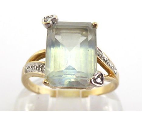 A blue topaz dress ring, the rectangular emerald cut stone 11 x 8mm, two claws terminating in a small single cut diamond and 