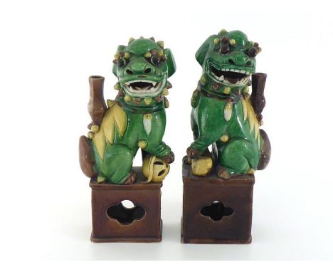 A pair of Chinese porcelain incense burners modelled as seated guardian lions on stands in three-coloured glaze, one a female