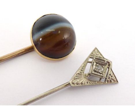 Two early 20th century stick pins, the first set with banded sardonyx, mounted in yellow metal (tests 9 carat gold); the seco