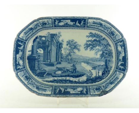 A 19th. century blue and white ceramic charger with a scene of a herdsman with his cattle passing a ruined classical temple, 