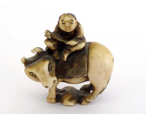 A Japanese stained ivory netsuke of a herdsman sitting on his buffalo.Signed on the base. 