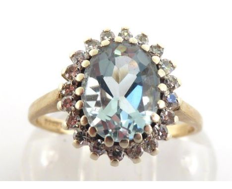 A 9 carat gold, aquamarine and diamond cluster ring, the central aqua 9 x 6.5mm, in a surround of small single but diamonds, 