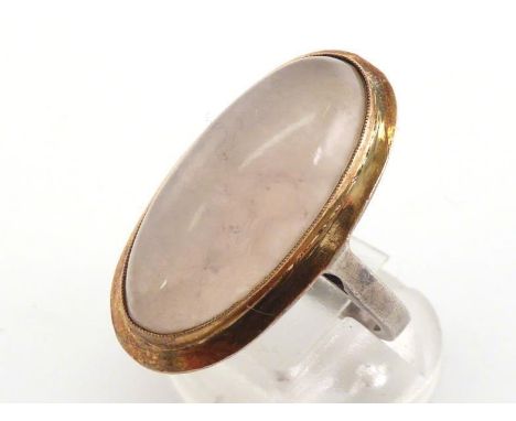 A French gold, silver and rose quartz ring, the central quartz oval cabochon 23 x 11mm, rub over set in gold, to a silver sha