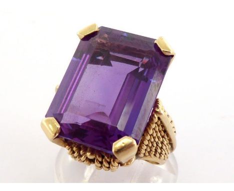 A synthetic colour change sapphire dress ring, the large emerald cut stone 20 x 15mm, claw set above a heavy shank (tests 14 