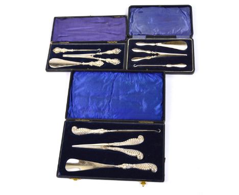 A cased Edward VII hallmarked silver sheath handled set of button hook, shoe horn and glove stretchers of shaped scrolling fo