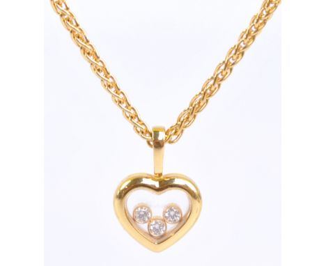 CHOPARD; an 18ct yellow gold framed heart shaped pendant with glazed aperture containing three round cut melee diamonds in be