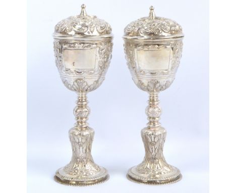 EDMUND JOHNSON; a pair of George V Irish hallmarked silver ciboria, each with domed cover above tapering bowl set with opposi