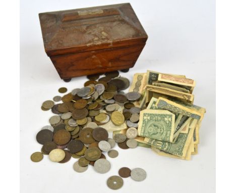 A collection of coins and bank notes contained within a distressed tea caddy.
