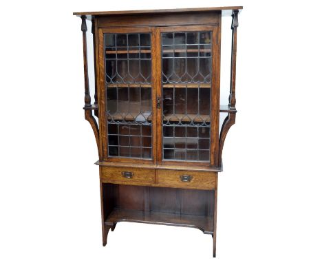 An early 20th century oak Arts and Crafts display cabinet, the moulded cornice above two leaded glazed doors with inverted he