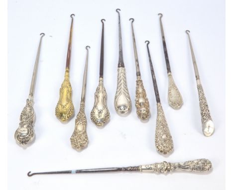 Ten large button hooks with hallmarked silver sheath handles, including a scroll decorated gilt washed example with monogram,