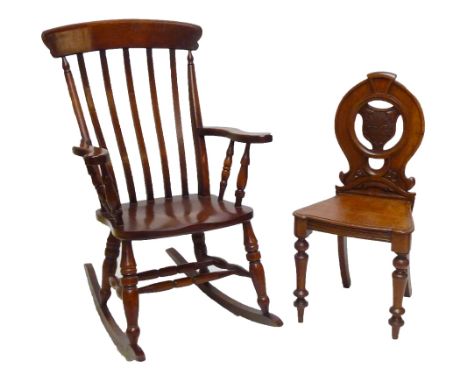 A Victorian oak hall chair with shield shape detail to the back, inscribed 'JWA', on ring turned supports, and a rocking chai