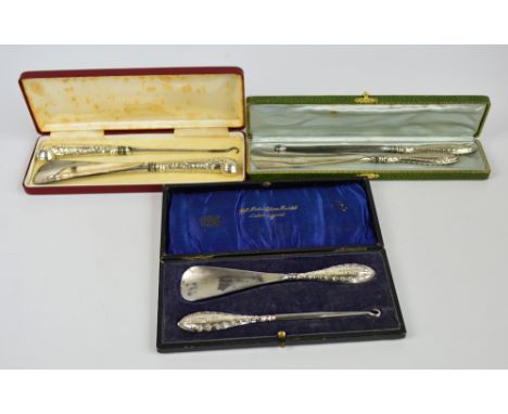 A cased Victorian hallmarked silver sheath handled set of button hook and shoe horn with pistol handle and monogrammed cartou