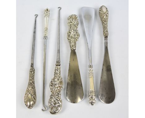 A Victorian hallmarked silver sheath handled set of shoe horn and button hook with cherub and floral motifs, William Comyns, 