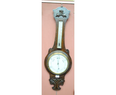 An early 20th century oak banjo barometer with carved foliate decoration with thermometer above circular gauge, height 89cm, 