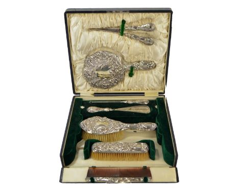 A cased George V hallmarked silver backed dressing table set, decorated with floral motifs in relief, comprising a hand mirro