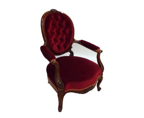 A late Victorian walnut spoon back armchair with oval button upholstered padded back, shaped seat and cabriole front legs.