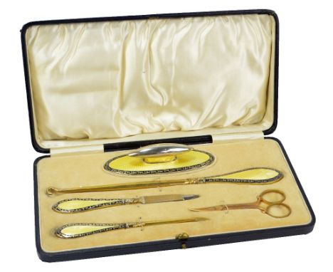 A cased George V hallmarked silver gilt and yellow guilloche enamel manicure set comprising a button hook, a nail file, a cut