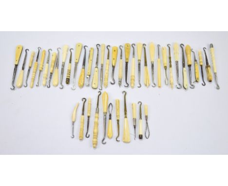 A collection of small button hooks, with ivory, faux ivory, and bone handles of various shapes, including folding examples. 