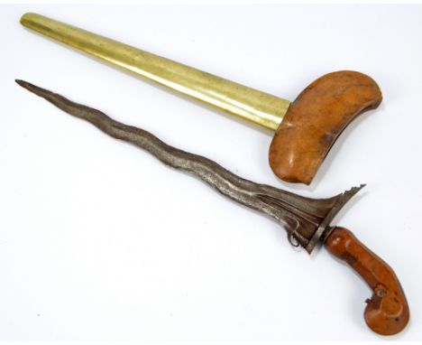 A 19th century North African kris, with carved shaped grip, shaped blade and brass bound wooden scabbard, length 51cm.