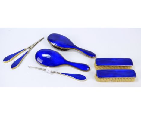 A George V hallmarked silver and royal blue guilloche enamel backed dressing table set, comprising two hand brushes, two clot