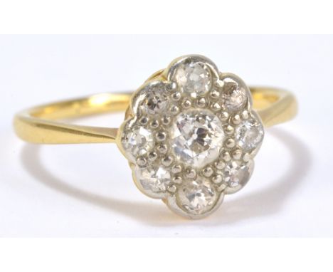 A yellow gold and diamond floral decorated ring, the central diamond weighing approx 0.10cts within a border of further diamo