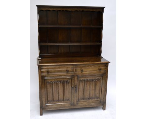 An oak dining room suite comprising a dresser with linen fold decoration, a dropleaf table, 153.5 x 90cm when extended, and a