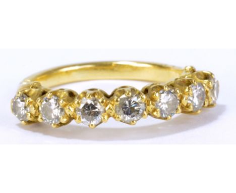 A yellow metal and diamond ring with seven round cut stones in claw setting, each approx 0.1ct, size M, approx 4g.