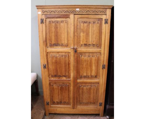 A carved light oak linen fold two door wardrobe